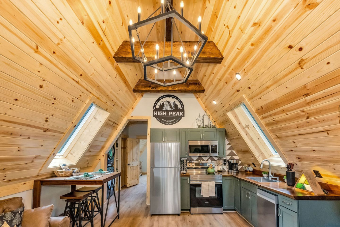 Open kitchen and living area with sage cabinets and High Peak logo