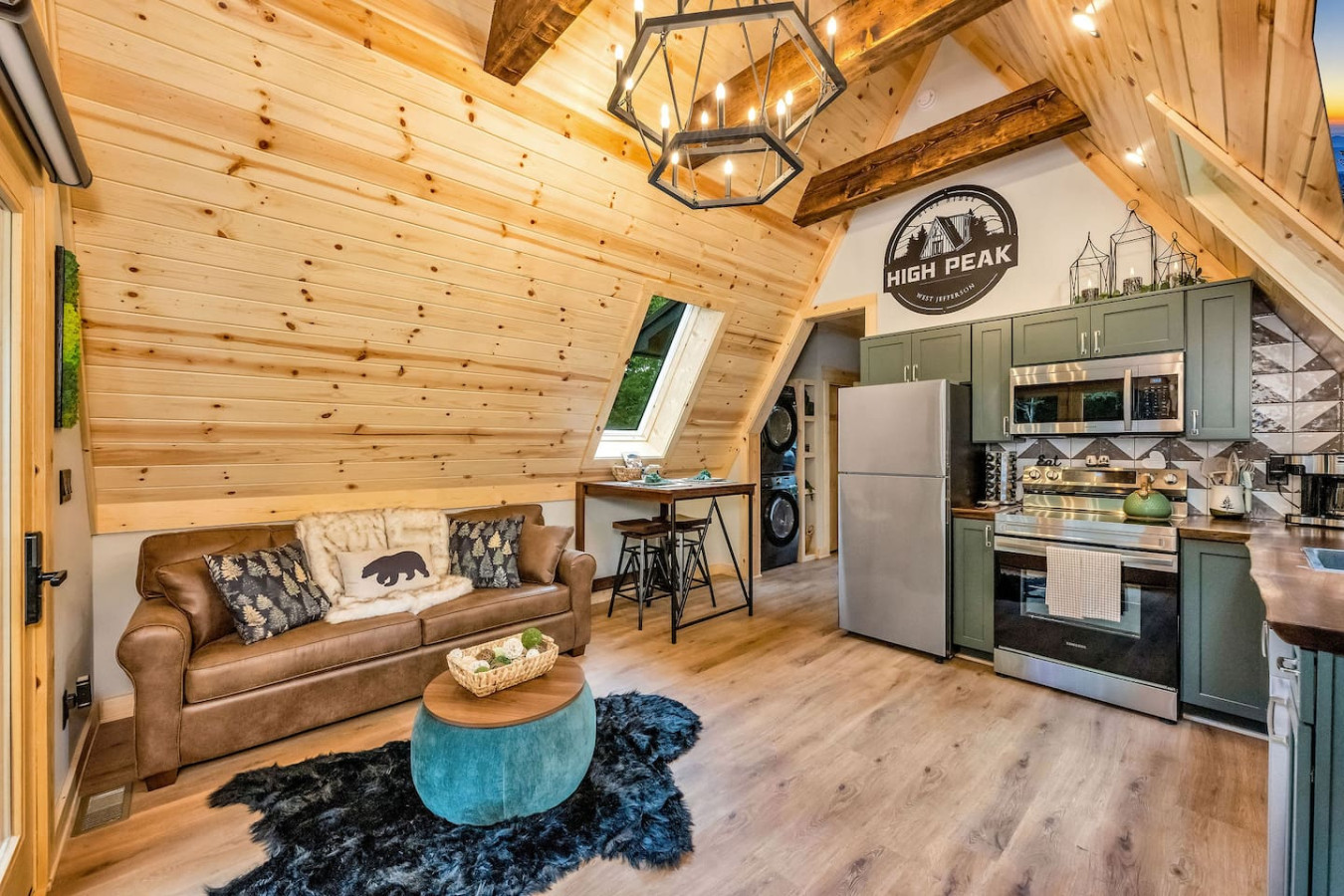 Open-concept living room, dining nook, and kitchen under vaulted wood ceilings