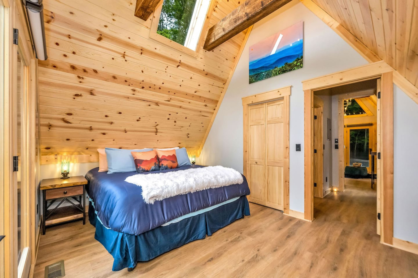 King bed under the A-frame skylight with mountain artwork