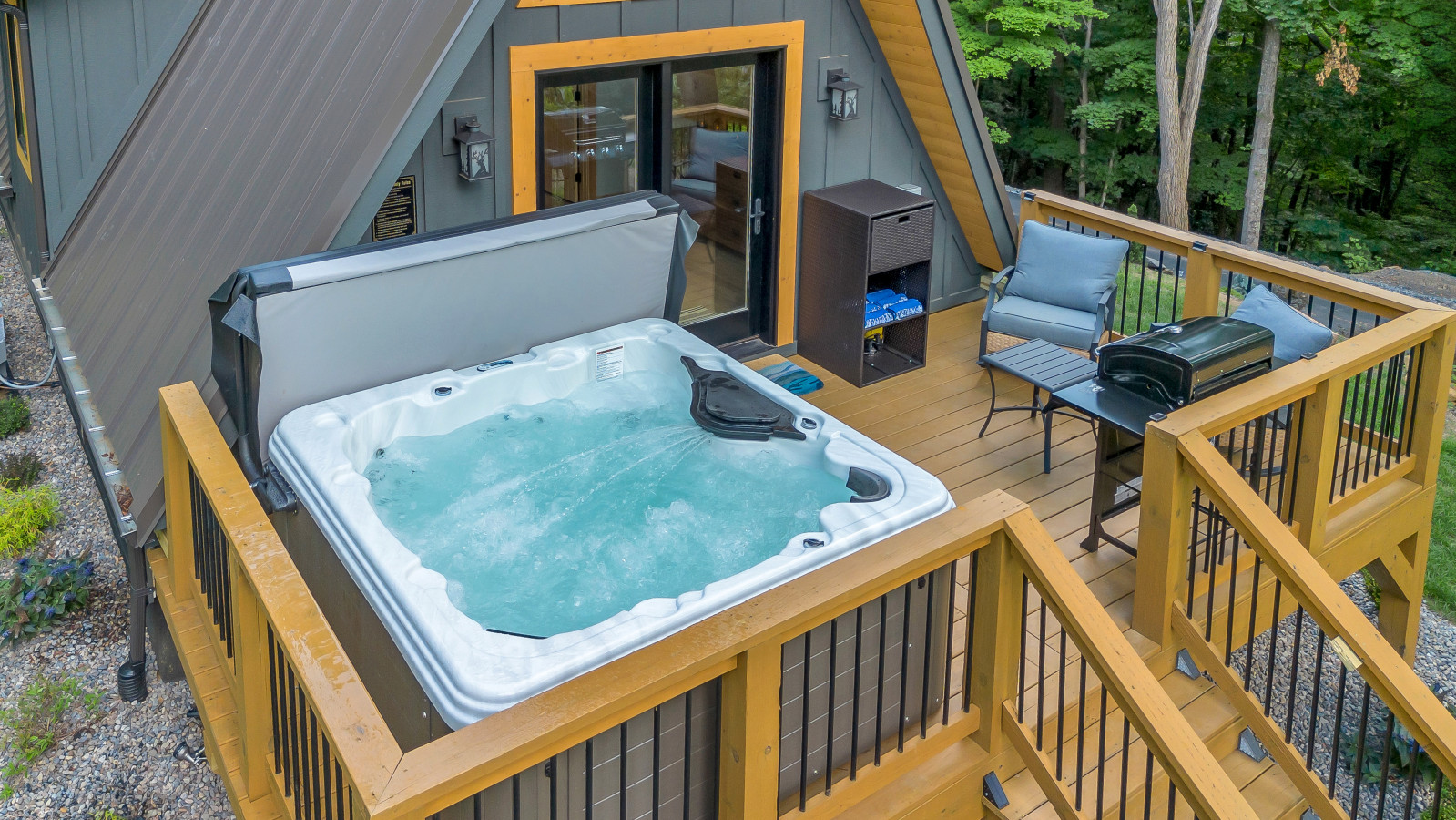 Bubbling XL hot tub on the High Peak deck with grill and lounge chairs