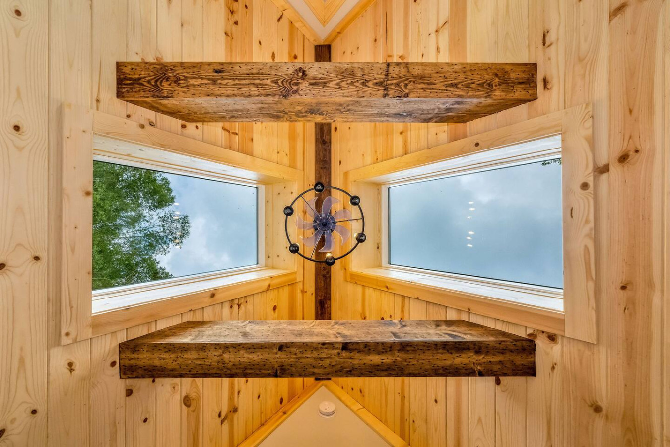 Looking up into the A-frame peak with timber beams and skylight fan