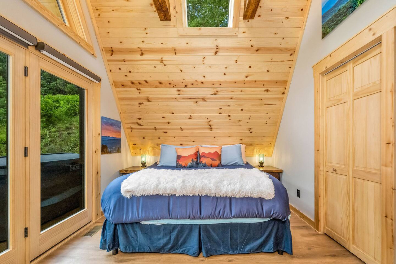 King bedroom with navy bedding, skylight, and glass doors to the deck