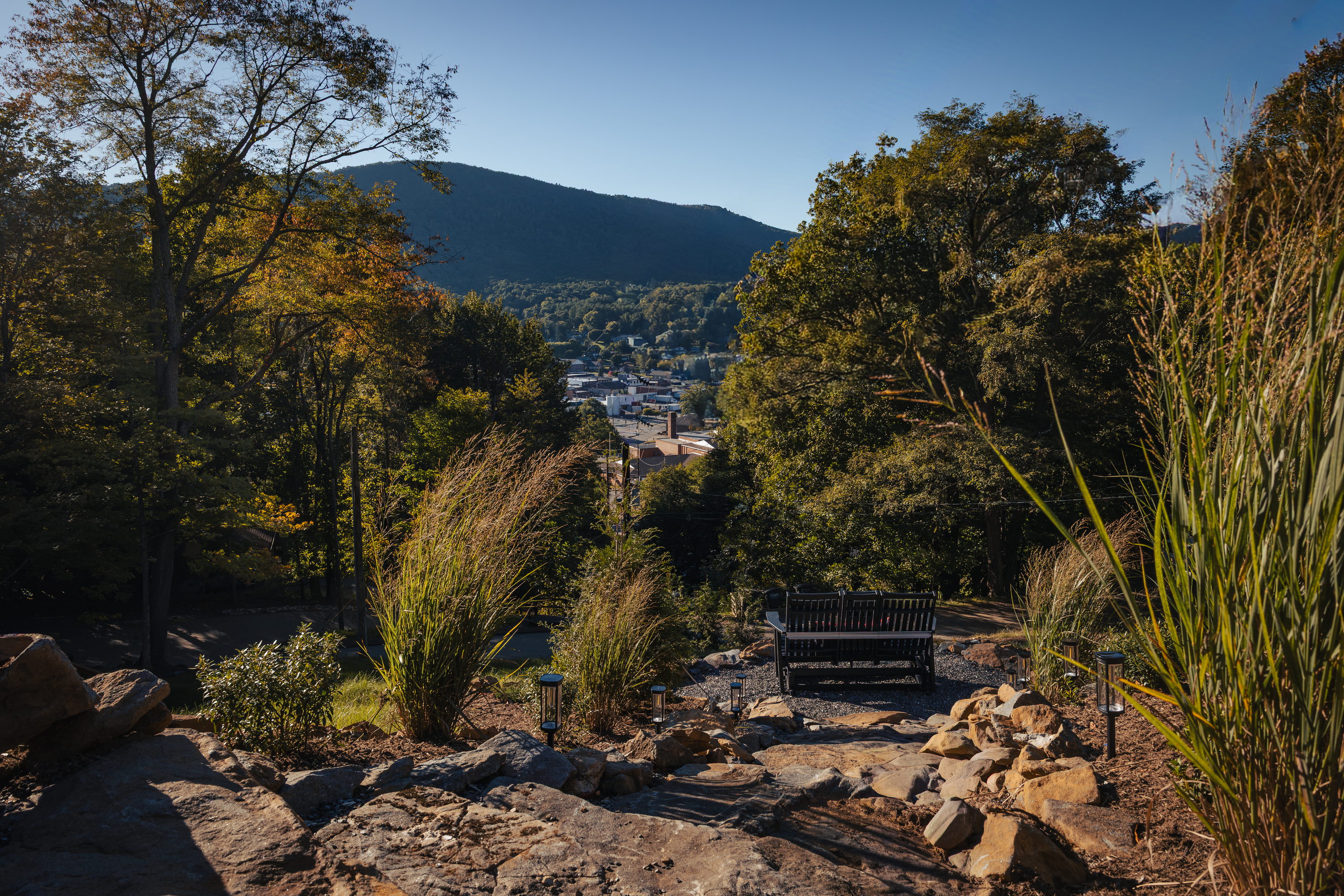 Bench on a rocky path looking toward town and a mountain at High Peak in West Jefferson, NC.